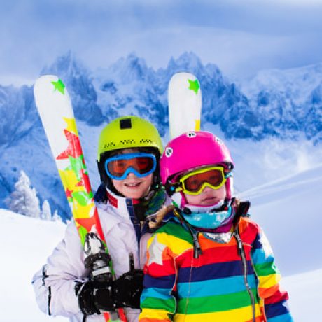 Boy and girl skiing in mountains. Toddler kid and teenager with helmet, goggles, poles. Ski race for children. Winter sport for family. Kids ski lesson in alpine school. Little skier racing in snow